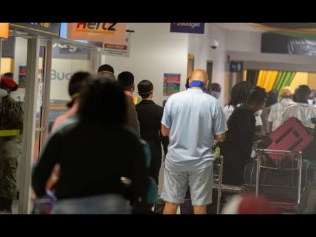 Jamaicans make their way through Norman Manley International Airport on Wednesday after returning to the island.