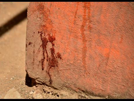 Credit: Kenyon Hemans A blood-stained wall shows the spot where 15-year-old Norville Hall fell after he was attacked on Sunday.