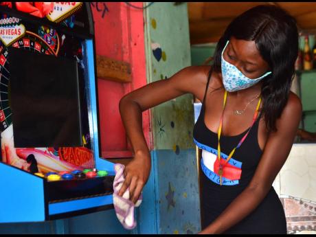 Credit: Kenyon Hemans Aniecia Smith wipes down a gaming machine as she prepares to open for business today.