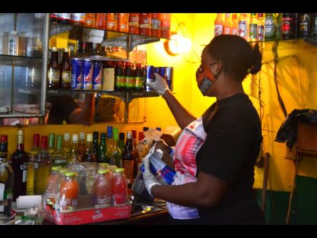 Credit: Kenyon Hemans Olivia Bartley, bartender at Myrna’s Place repacks the shelves in anticipation of opening today.