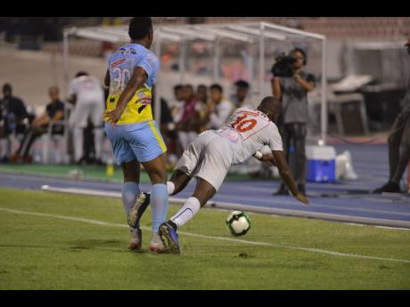 Waterhouse defender Shawn Lawes (left) sends Portmore United striker Javon East tumbling to the ground after a challenge during the Red Stripe Premier League final at the National Stadium on April 29, 2019. 