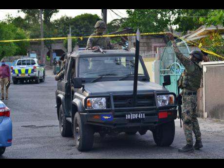 Soldiers patrol a section of August Town, St Andrew, where a disabled woman died, allegedly at the hands of the security forces yesterday. 
