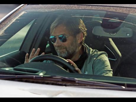 Liverpool manager Jurgen Klopp waves as he arrives at the club’s Melwood training ground after the English Premier League announced players can return to training in small groups as the coronavirus lockdown was eased on Wednesday May 20. 
