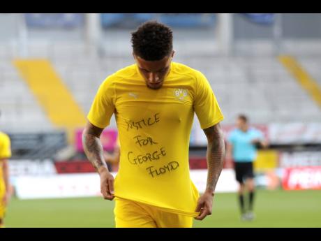 Jadon Sancho of Borussia Dortmund celebrates scoring his team’s second goal of the game with a ‘Justice for George Floyd’ shirt during the German Bundesliga match between SC Paderborn 07 and Borussia Dortmund at Benteler Arena in Paderborn, Germany, Sunday, May 31, 2020. 