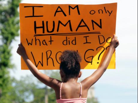 Rylie Blue holds a sign during a Black Lives Matter march and rally yesterday.