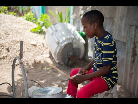 Anthone raps on his home-made drum set at his home in Central Village, St Catherine.