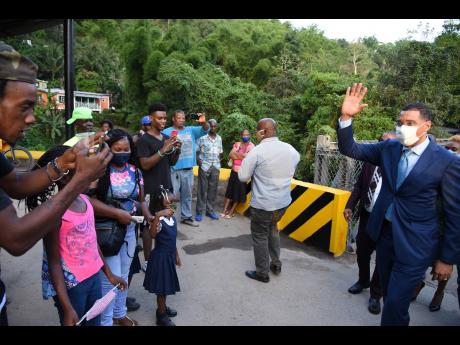 Prime Minister Andrew Holness waves to residents of Bowden Hill shortly after the opening of the Bowden Hill Bridge on Thursday.