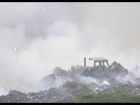 A tractor moves dirt to cover a fire at the Riverton City dump in the Corporate Area.