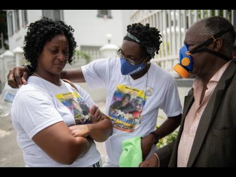Yanike Crosdale (left), mother of the late Jevaughn Duhaney, is consoled by Leon Duncan (centre) as they wait for Duhaney’s autopsy to be done at the House of Tranquillity Funeral Home in Kingston yesterday. Looking on is Dr Jephthah Ford.