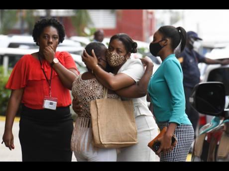 Mourners grieve on the compound of the Kingston Public Hospital shortly after getting news of the death of Superintendent Leon Clunis yesterday.