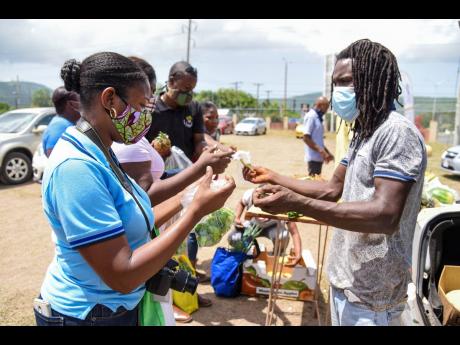 Farmer from East Kirkland Heights, St Andrew, Glenroy Crossman (right), collects money from patron, Denisha Bourne, during a farmers’ market last Friday at the Agriculture Ministry’s playing field in Mona. 