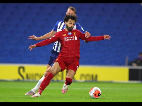 Liverpool’s Mohamed Salah (foreground) takes the ball away from Brighton’s Dan Burn during the English Premier League match between Brighton and Liverpool at Falmer Stadium in Brighton, England, yesterday. Liverpool won 3-1.