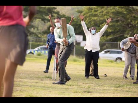 Prime Minister Andrew Holness shows off his flashing blade against members of a women’s cricket team at Eden Park Sports Complex in St Mary last week.