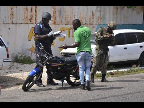 Members of the security forces conduct stop and search operations at the intersection of Charles and James streets in Kingston on Saturday.