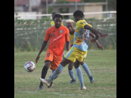 Tivoli Garden’s Jermaine Johnson makes a pass while  Waterhouse player Colorado Murray  moves in, during their  Red Stripe Premier League encounter at the Edward Seaga Complex.