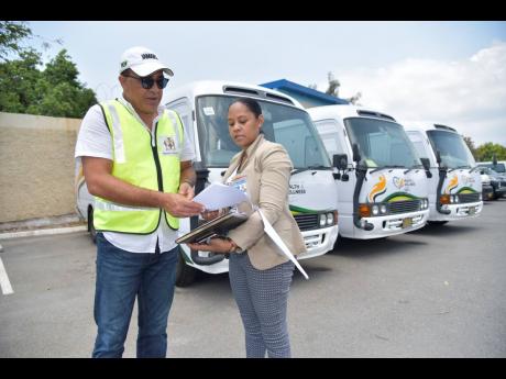Minister of Health and Wellness, Dr  Christopher Tufton, looks at a document being shown to him by coordinator of medical technology services in the ministry, Mitchelle Maylor Archat. 