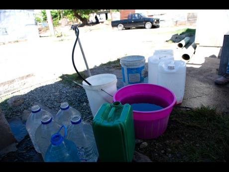 Residents top up their containers from the only pipe with running water in a section of Tivoli Gardens.