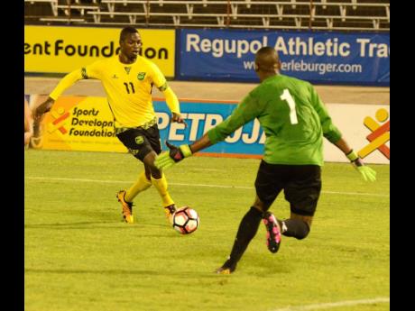 Corey Burke (left) tries to get past the Suriname goalkeeper Cladel Kohinor during the Caribbean Cup qualifier at the National Stadium in 2016.