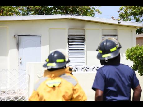 
Firemen look at a house in Bridgeport, St Catherine, where Karen Nugent died in a blaze yesterday.