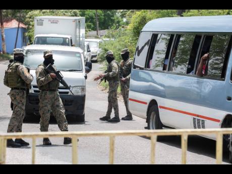 Members of the Jamaica Defence Force check motorists at one of several checkpoints erected in the Sandy Bay community in Clarendon on Thursday. A 14-day lockdown has been imposed on the community following several positive COVID results.