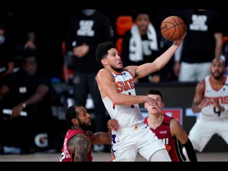 AP
Phoenix Suns’ Devin Booker goes to the basket over Miami Heat’s Andre Iguodala (left) and Tyler Herro (right) during the second half of an NBA basketball game on Saturday, August 8, in Lake Buena Vista, Florida. 