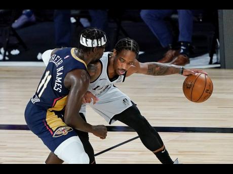 San Antonio Spurs forward DeMar DeRozan (right) tries to keep the ball away from New Orleans Pelicans guard Jrue Holiday (11) during the second half of an NBA basketball game, Sunday, August 9, 2020.