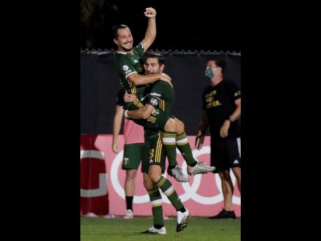 Portland Timbers midfielder Sebastian Blanco, top, celebrates his goal with Diego Valeri against the Philadelphia Union during the second half of an MLS soccer match, Wednesday, Aug. 5, 2020, in Kissimmee, Florida.