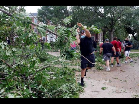 Joshua Robles clears trees with other members of the Coe College football team from campus sidewalks in Cedar Rapids after a powerful storm with straight-line winds moved through Iowa on Monday.