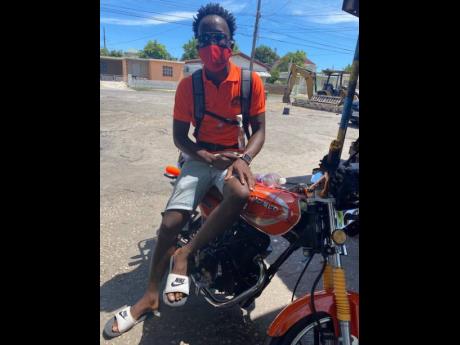 Credit: Akera Davis PNP supporter Junior Gayle shows off his orange motorbike.