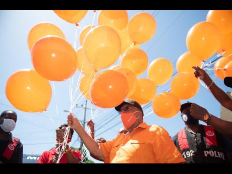 Dr Peter Phillips, People’s National Party leader and incumbent for St Andrew East Central, releases orange confetti-filled balloons outside the nomination centre, Tarrant Baptist Church, following his successful nomination.