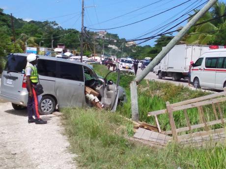 Credit: Hopeton Bucknor A policeman views the crash scene where McNeil Kerr lost his life on Tuesday morning.