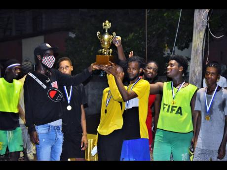 Photo by Anthony Minott 
Tower Hill Strikers celebrate after winning the inaugural Memorial Cup with main organiser Rohan Reid, also known as Young Wild Apache (left).
