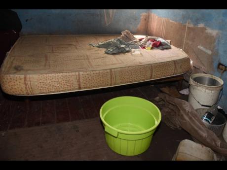 Credit: Kenyon Hemans A bath pan and a bucket positioned in the house to catch rainwater from the leaking roof.