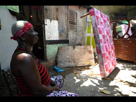 Nichola Pink’s mother, Patricia Shaw, is at a loss for words as she sits in the yard where the couple lived in Chestnut Lane, Denham Town.