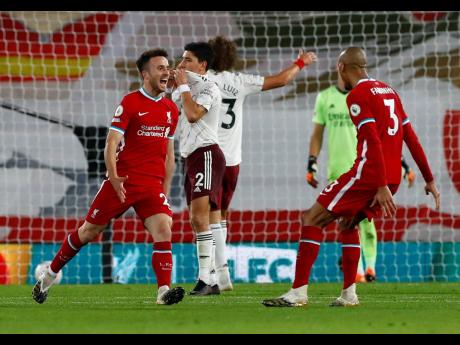 Liverpool’s Diogo Jota (left) is congratulated by teammate Fabinho after scoring his team’s third goal during the English Premier League match against Arsenal at Anfield in Liverpool, England, yesterday.