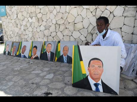 Credit: Ricardo Makyn Linstead artist Nigel Easy shows off his paintings of popular figures in the Jamaican Government, outside the Jamaica Conference Centre on Tuesday.
