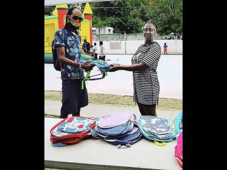Kid Kurup hands over a school bag to a resident of Standpipe.