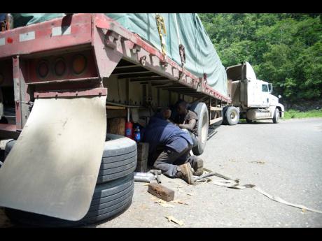 Mechanics try to get the truck rolling after it broke down on the Flat Bridge in St Catherine.