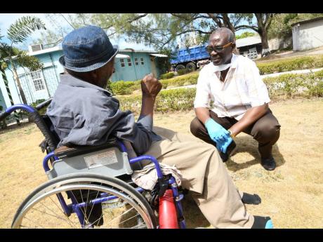 Credit: File Desmond McKenzie, the minister of local government, talks to a resident of the Golden Age Home in Vineyard Town, Kingston, on March 30, a few weeks after Jamaica recorded its first COVID-19 case.