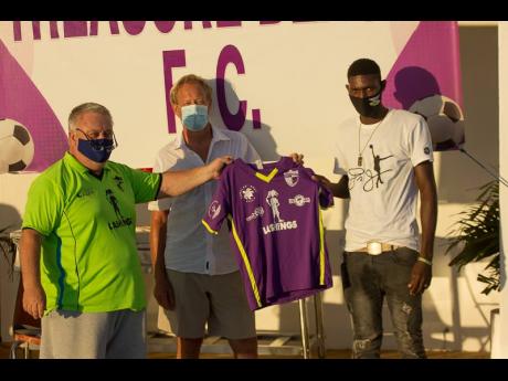 Treasure Beach FC President David Folb (left) and board member Brian Miller present new signing Romario Smith with his Treasure Beach FC jersey.