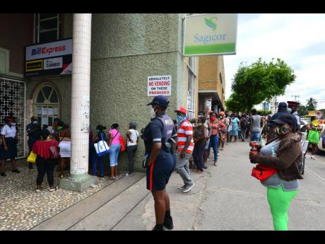 Persons waiting to get inside a Western Union outlet in Spanish Town in April.