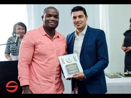 Kadian Willie (left) receives a plaque for long service from Jorge Camelo, human resources manager at Carib Cement.