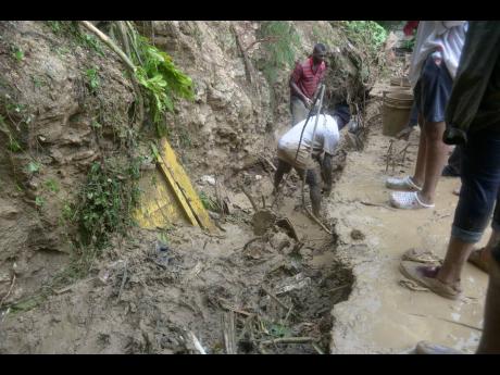 In this October 23 photo, Residents of Shooters Hill in Bull Bay dig away mud and debris after a landslide. 