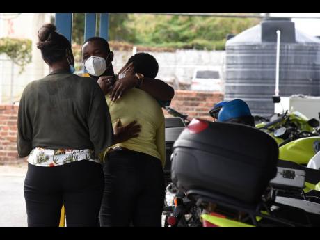 A family member of the late Constable Fabian Morrison of the Public Safety and Traffic Enforcement Branch is consoled by a police officer as she was overcome with grief at Elletson Road Police Station yesterday.