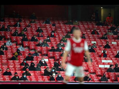 Credit: AP Arsenal fans sit in spaced out seats for coronavirus rules during an English Premier League match between Arsenal and Burnley at the Emirates stadium in London, England, on Sunday, December 13, 2020.