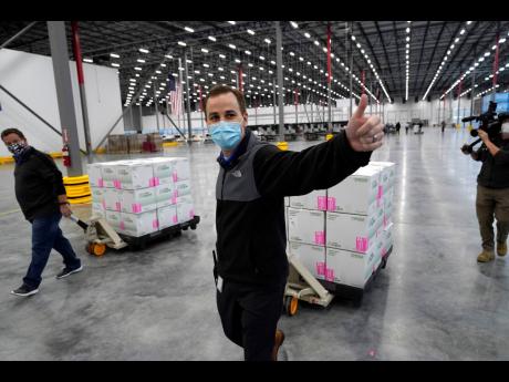A worker gives a thumbs up while transporting boxes containing the Moderna COVID-19 vaccine to the loading dock for shipping at the McKesson distribution centre in Olive Branch, Mississippi, yesterday. It is expected to be given out starting today. The Pfizer and BioNTech vaccine was rolled out last week.
(AP Photo/Paul Sancya, Pool)