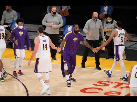 Los Angeles Lakers forward LeBron James greets his teammates from the bench during an NBA preseason basketball game against the Los Angeles Clippers in Los Angeles, Sunday, December 13, 2020. 