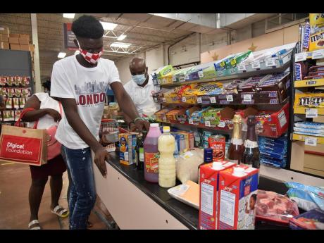 Tussan Smart (left) loads some of the groceries for the cashier with assistance from Digicel’s Elon Parkinson (background). 