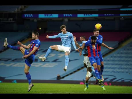 Manchester City’s John Stones (centre), heads the ball to score his side’s opening goal during an English Premier League football match between Manchester City and Crystal Palace at the Etihad Stadium in Manchester, England,  yesterday.