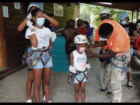 Mom, Toni (partially hidden) helps birthday girl, Tori, to get ready for the zip line, while little Teahira gets help from a Chukka team member.    